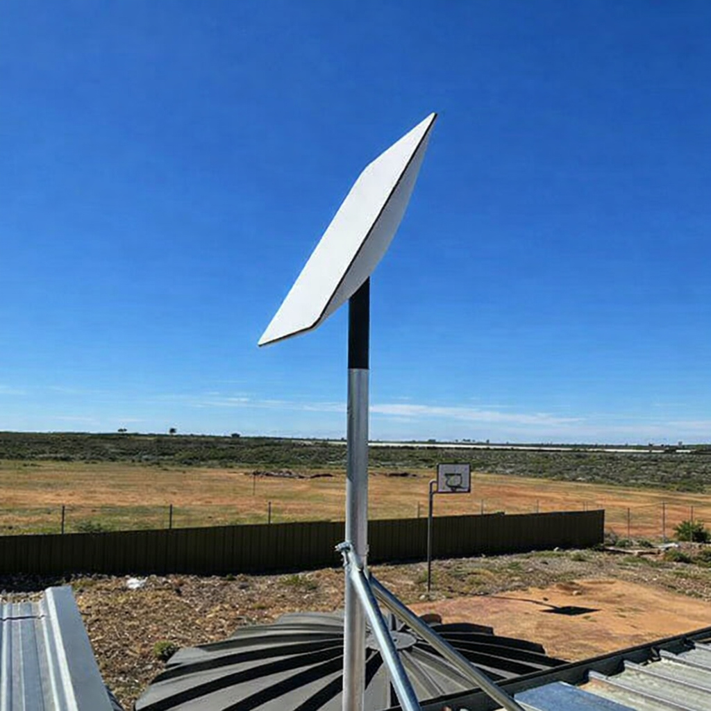 Starlink GEN 2 dish mounted on a metal pole on a rooftop, angled toward the sky in a rural outdoor setting