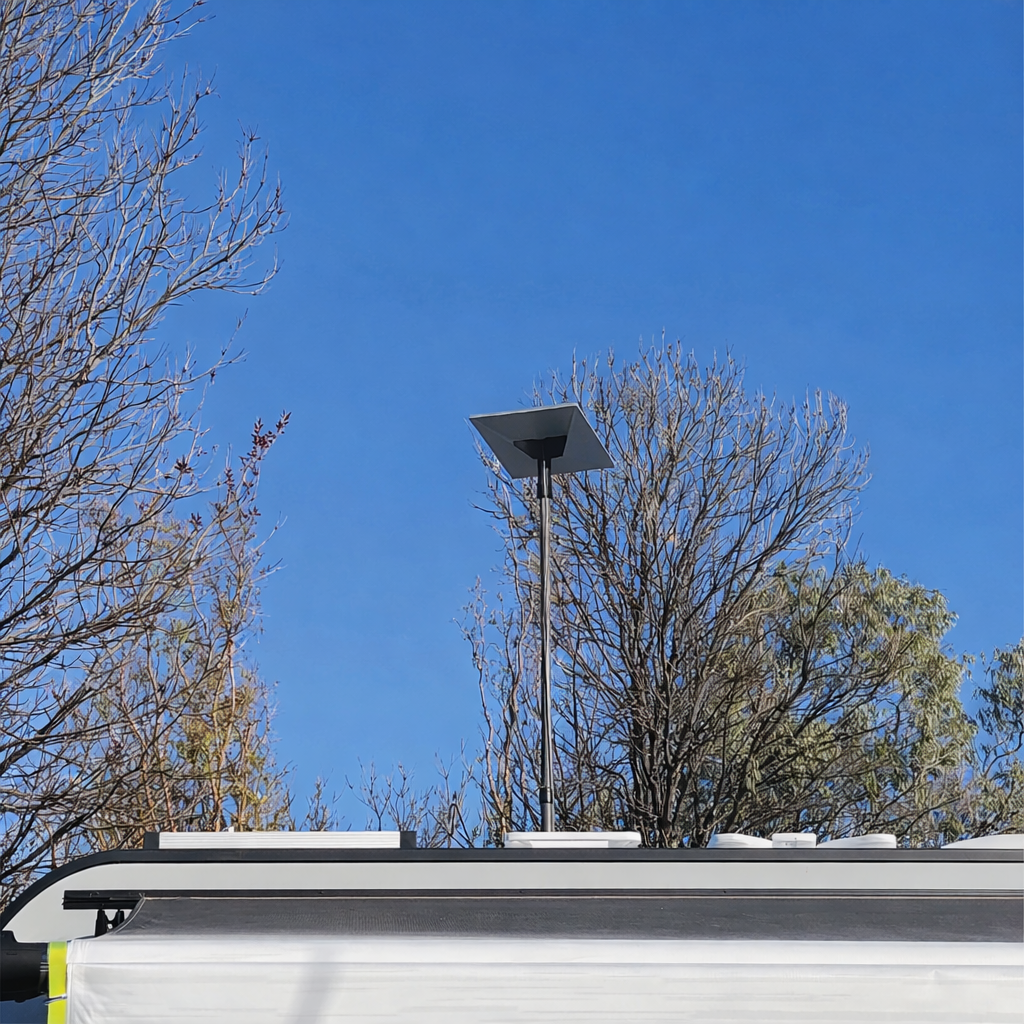 Starlink receiver mounted on Spacetek carbon fibre telescopic pole installed on caravan roof in outdoor camping setting