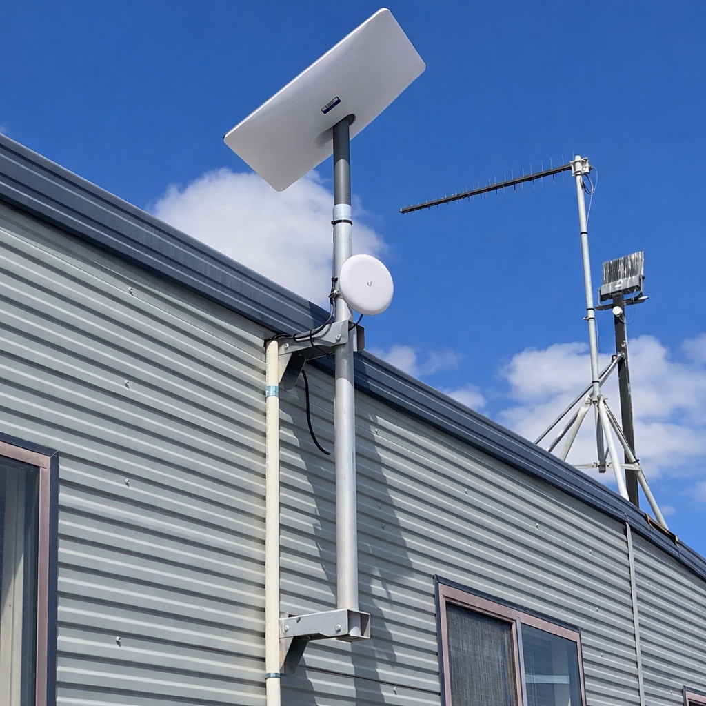 Starlink satellite dish mounted on external wall using galvanized steel pole bracket on metal building exterior