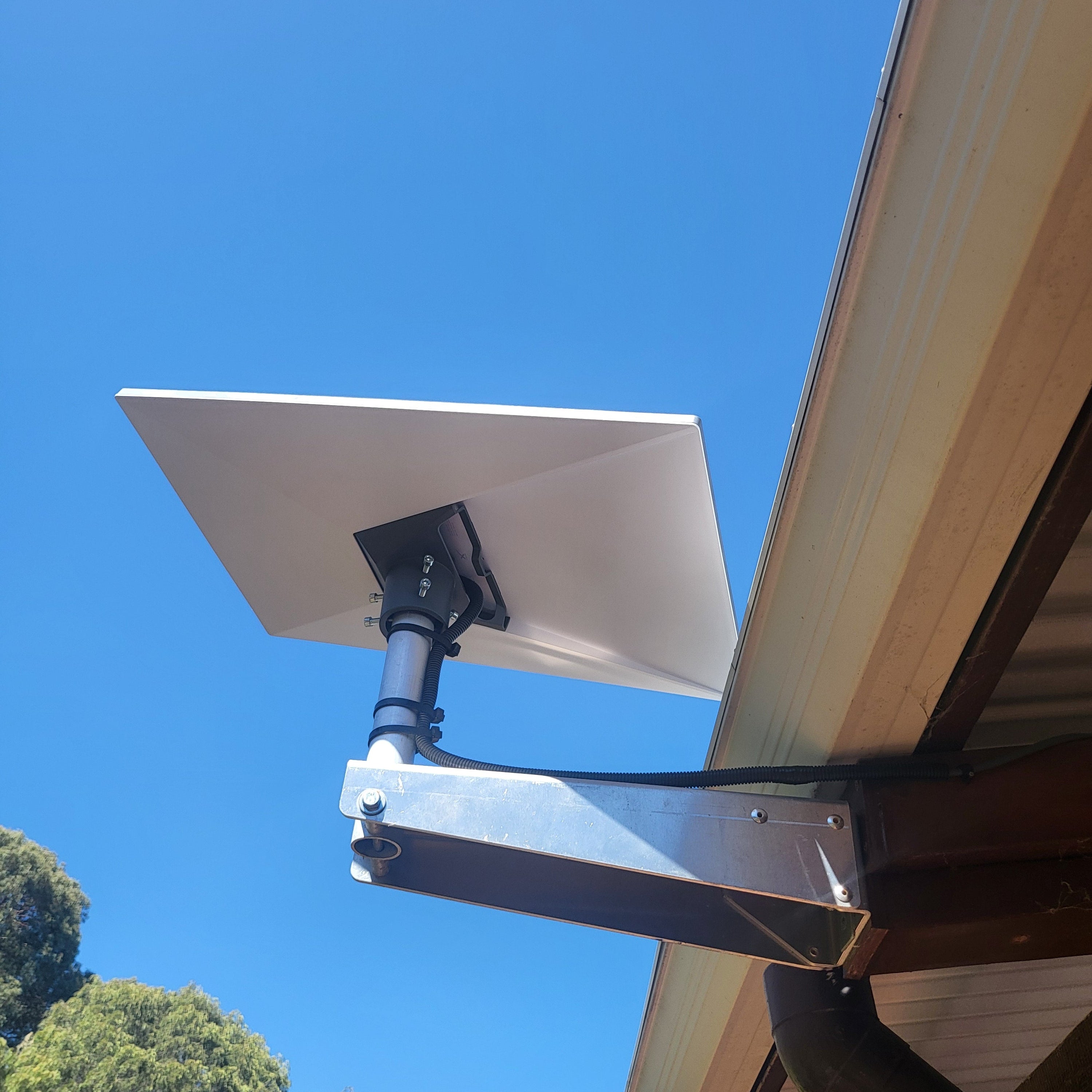 A photo of a Starlink Gen 3 Wall Mount kit under an eave in a residential setting. 