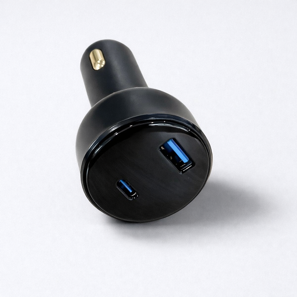 Close-up of the Spacetek dual-port car charger featuring USB-C and USB-A ports on a glossy black faceplate with a gold tip, presented on a light grey backdrop