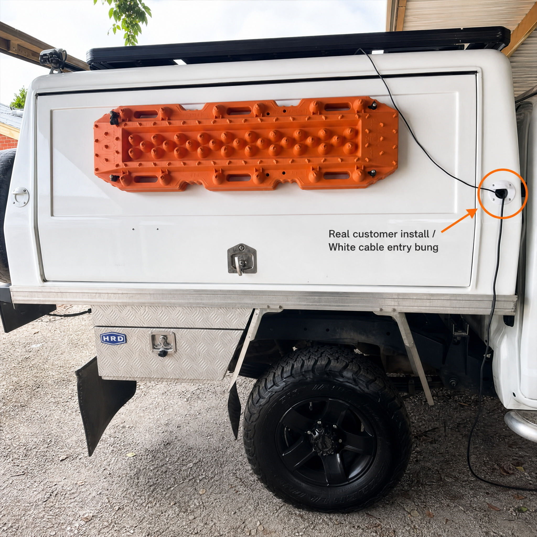 White Spacetek cable entry bung installed on a truck canopy with cable routed through the bung